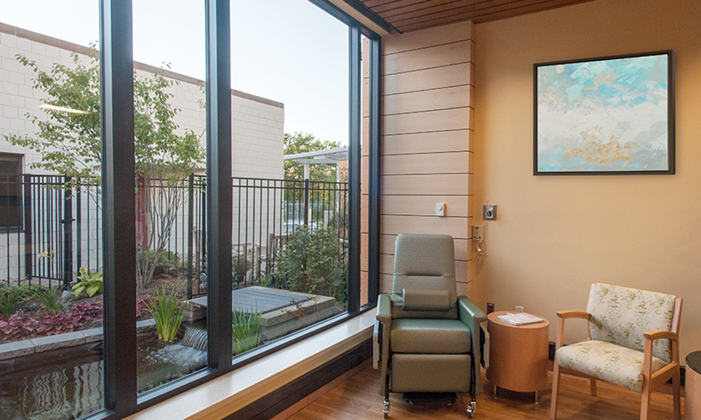 <p>Large wooden beams span across the ceiling of medical oncology, connecting infusion bays and nursing stations to the garden. The ceiling between the beams rises to meet the exterior windows, maximizing the natural light to the area. </p>
