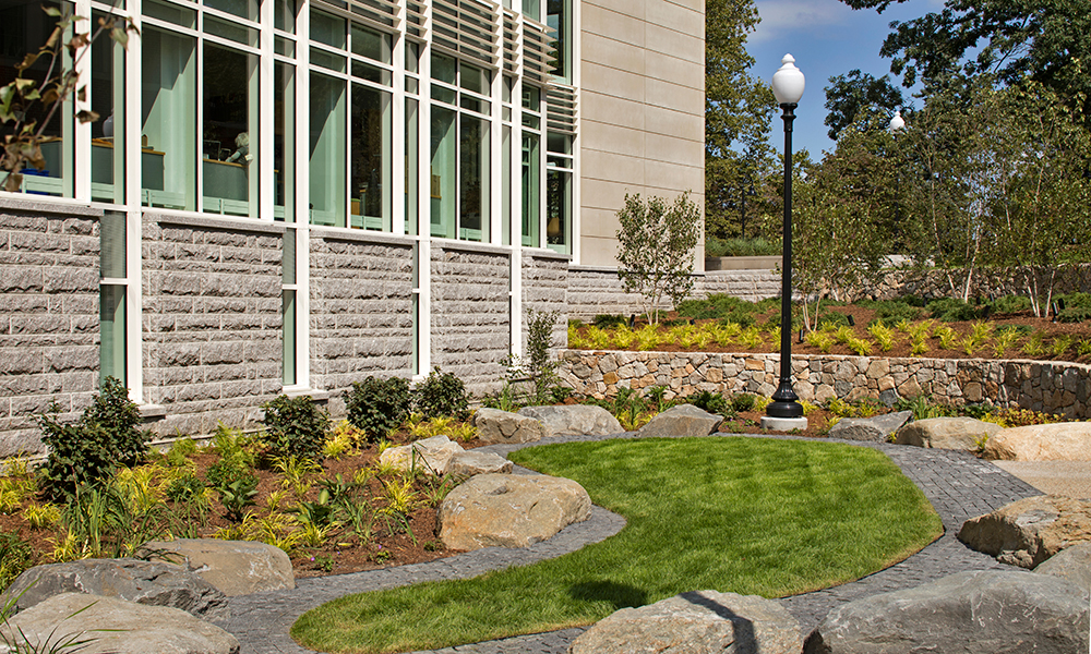 <p>A sunken garden provides egress from the lower level while featuring a paisley-shaped lawn seating area surrounded by gray birch and terraced walls.</p>
