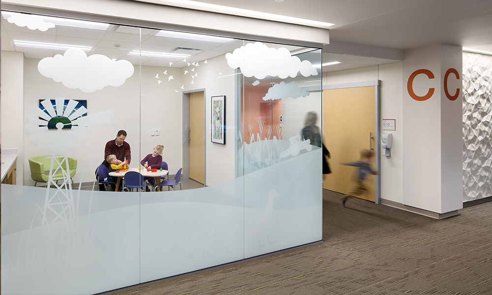 <p>A playroom encourages lively activities in a defined space, while providing clear visibility from the waiting area through glass coated with environmental graphics.</p>
