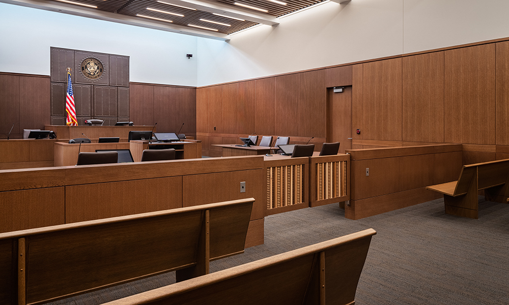 <p>The courtroom sightlines are enhanced by placing the clerks in front of the bench at ground level. The two-tiered jury and witness box sit above ground level, and the Judge sits highest above all. The hierarchy of levels improves visibility for all in the space. Natural daylight is provided from both from clerestory and transoms over the courtroom entry doors.</p>
