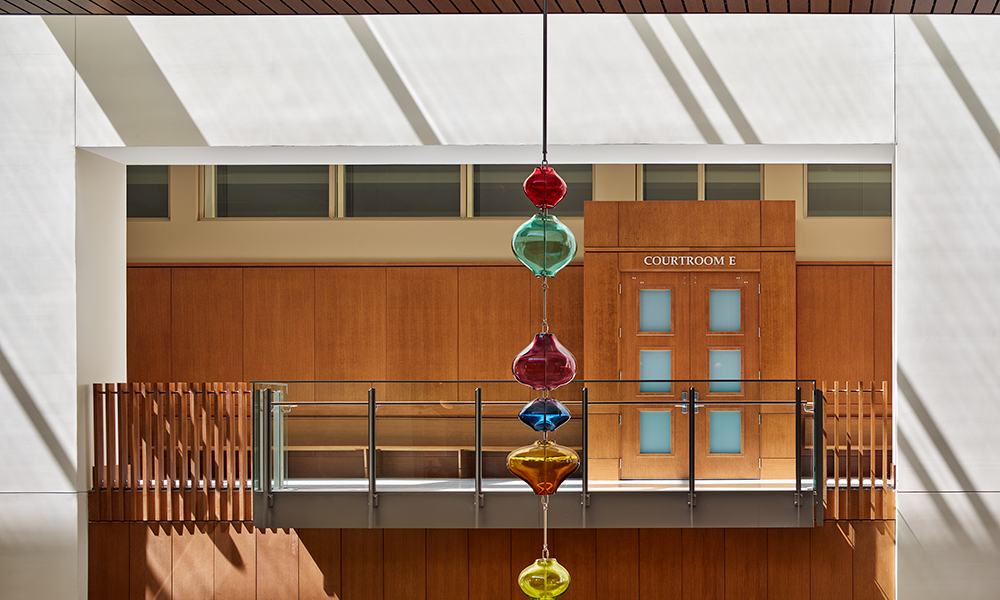 <p>Reflecting the ordered pilasters outside, 50’ tall interior pilasters frame views into courtrooms through oak slats that warm the atrium while filtering light into the courtroom gallery from the continuous skylight above.</p>
